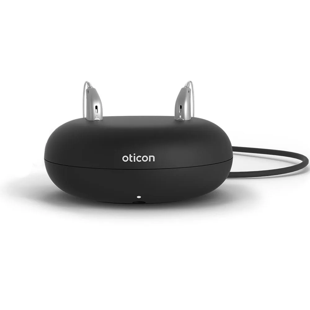 Oticon charging case with two silver hearing aids docked