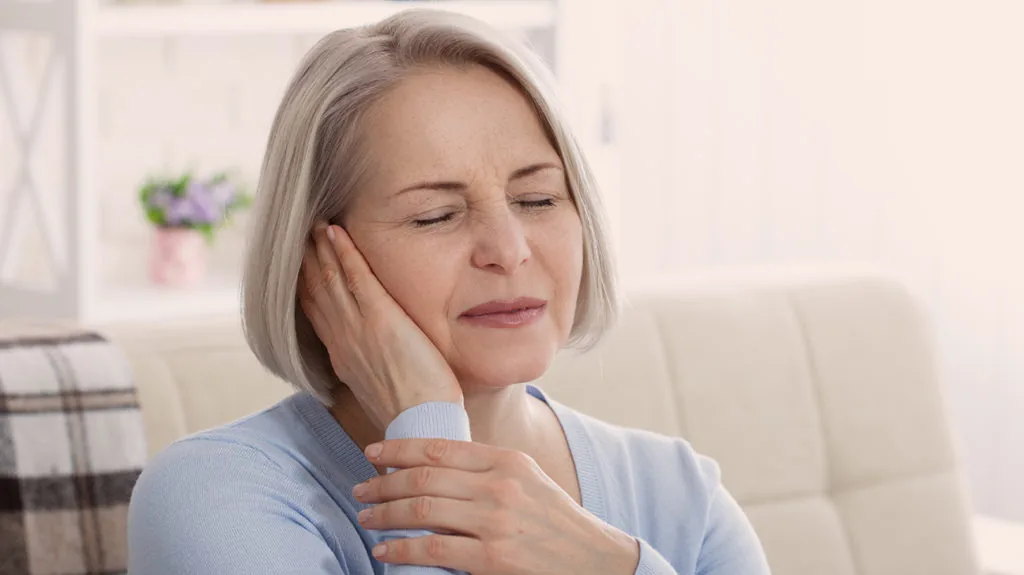 Woman holding jaw in pain suggesting TMJ discomfort