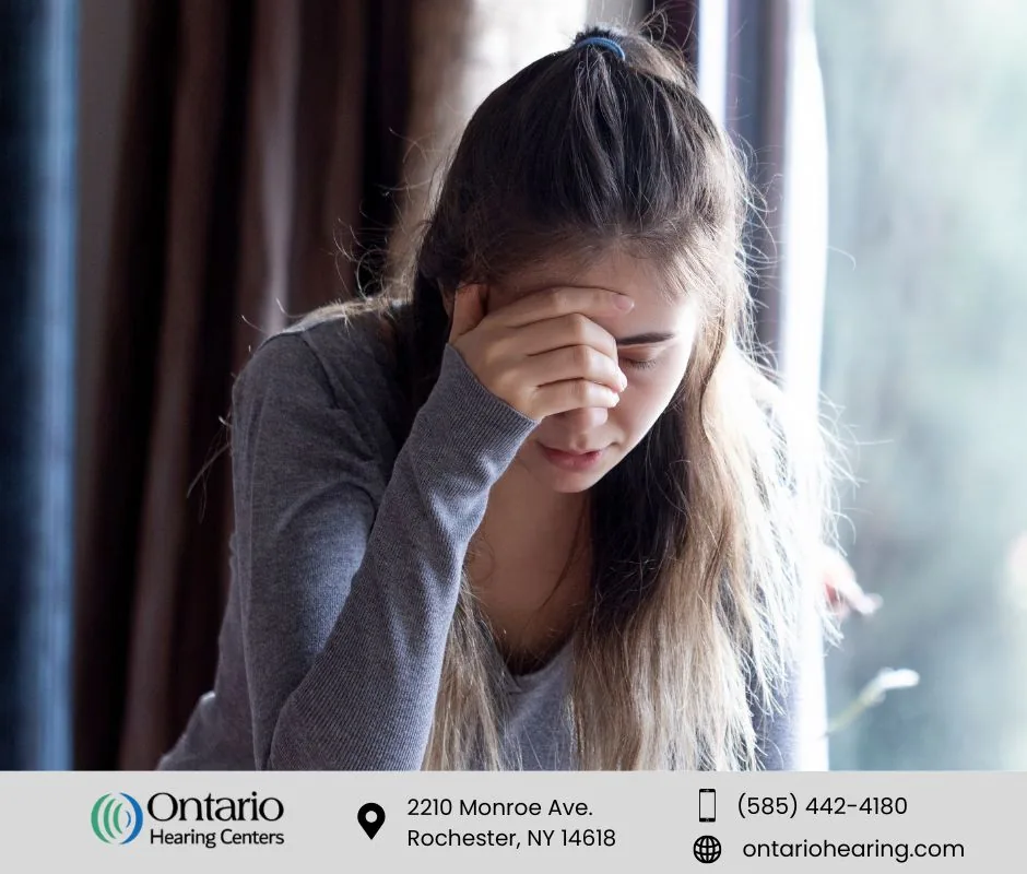 Woman holding her forehead and closing her eyes, appearing to be in pain or experiencing dizziness.