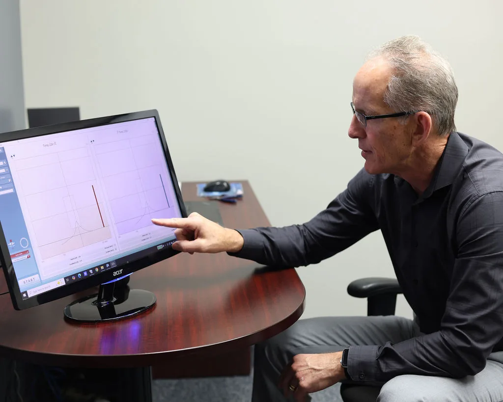 Audiologist pointing at hearing test data on monitor