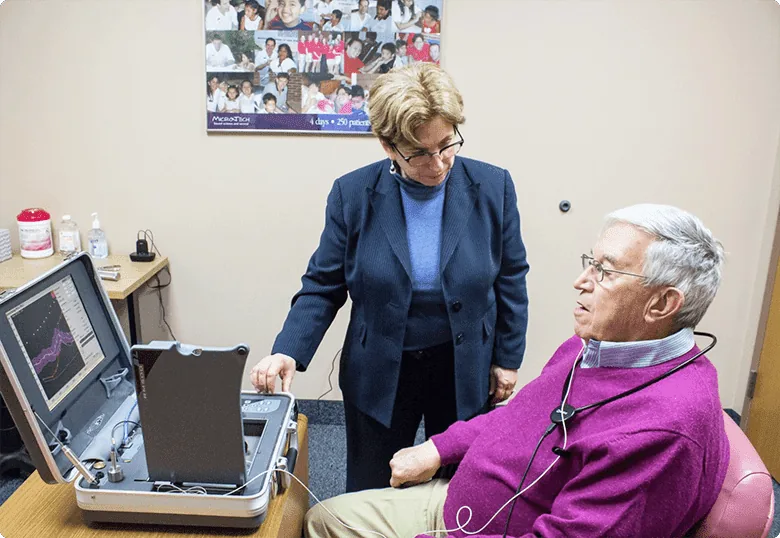 Audiologist fitting hearing aid using portable computer for adjustments
