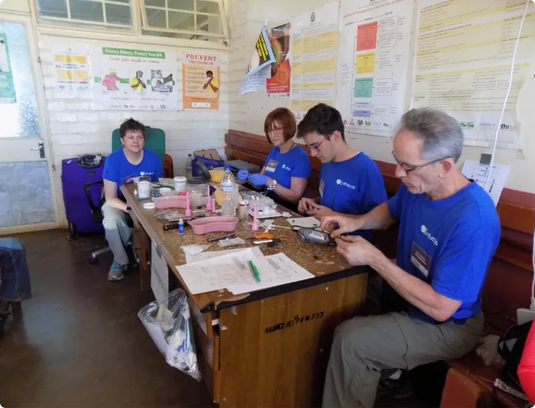 Volunteers in blue t-shirts working at clinic table with medical supplies