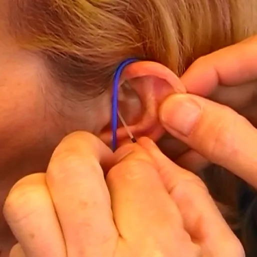 Hands fitting hearing aid tube into child ear for real ear measurement