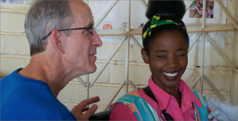 Older man and young woman smiling in humanitarian clinic setting
