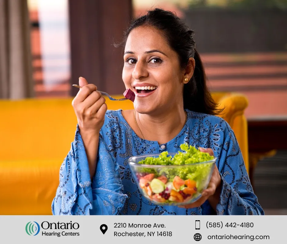 An image of a woman eating salad smiling