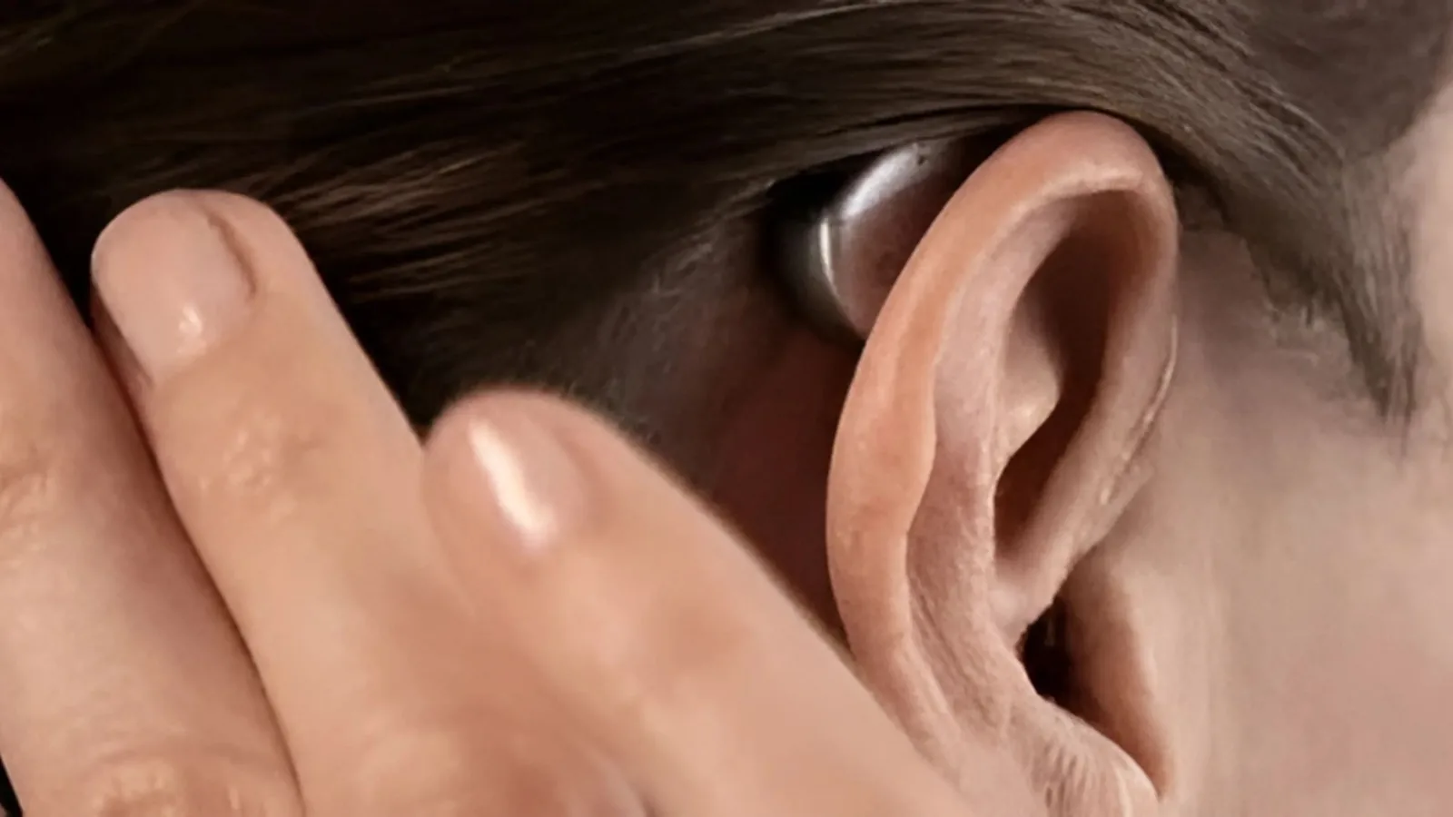 Hand placing Widex Moment Sheer hearing aid into ear