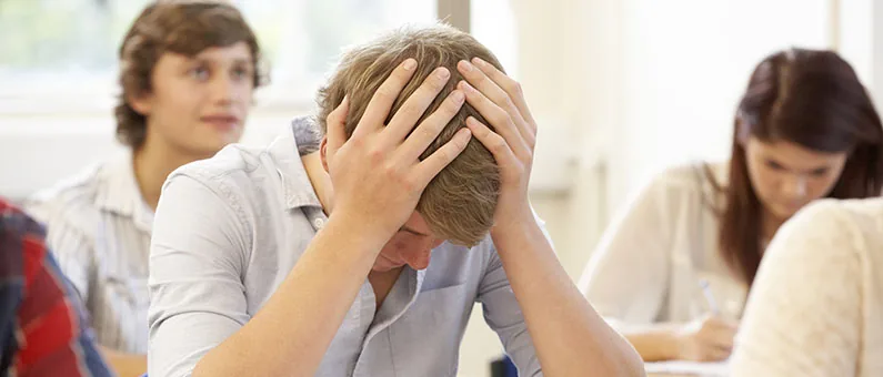 Student clutching head in frustration during class