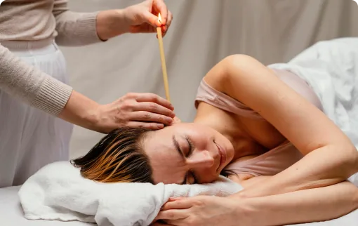 Woman receiving ear candling treatment