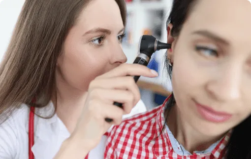 Doctor examining patient ear with otoscope