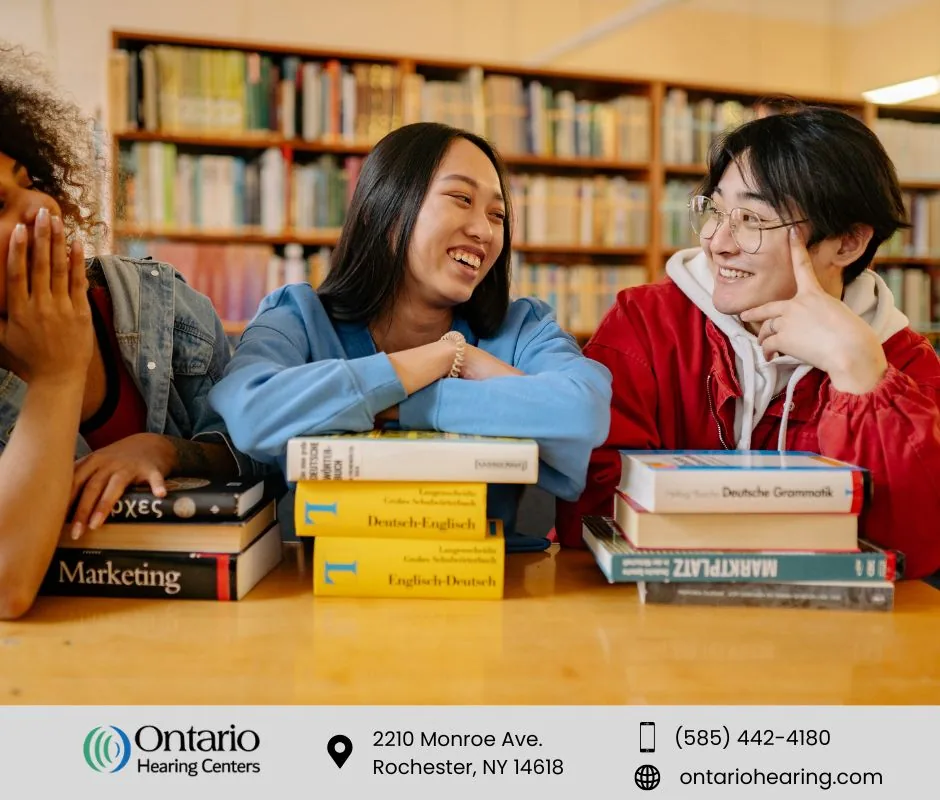Three happy students laughing and talking in a library