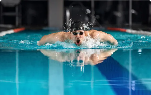 Swimmer performing butterfly stroke in indoor pool