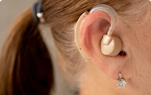 Woman wearing beige behind-the-ear hearing aid close-up