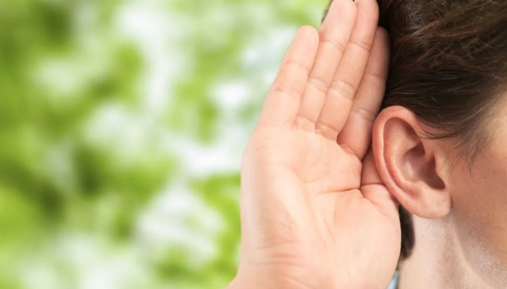 Person cupping hand behind ear in listening gesture