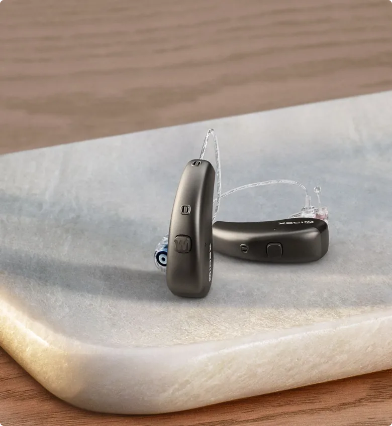 Widex Moment dark gray behind-the-ear hearing aids on marble